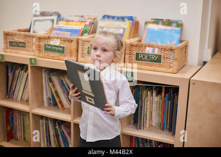 Schoolgirl in a uniform holding a book and walking on a rope isolated ...