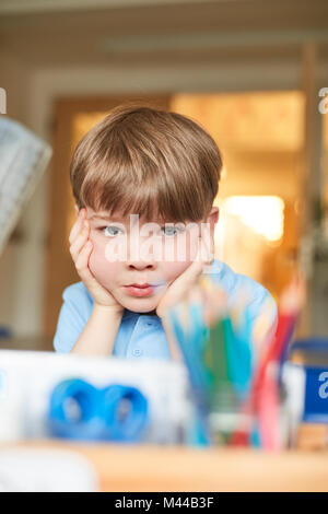 Schoolboy with chin on hands in classroom at primary school, portrait Stock Photo