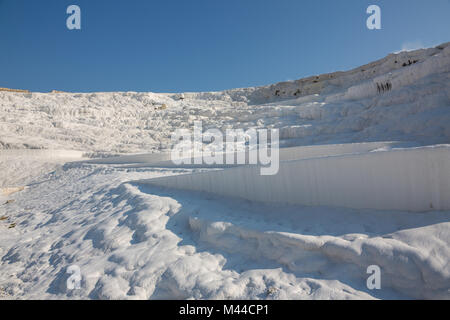 The enchanting pools of Pamukkale in Turkey. Pamukkale contains hot springs and travertines, terraces of carbonate minerals left by the flowing water. The site is a UNESCO World Heritage Site. Stock Photo