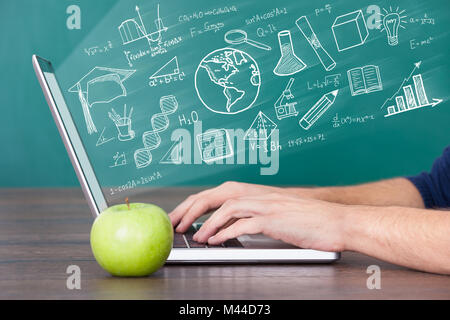 Close-up Of A Man Using Laptop Computer With Green Apple On Desk Stock Photo