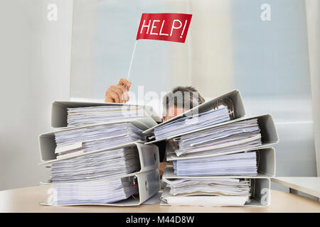 Stack Of Folders In Front Of Businessman Holding Red Flag With Help Text Stock Photo
