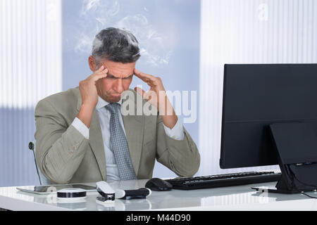 An Angry Stressed Businessman Sitting On Chair At Workplace Stock Photo