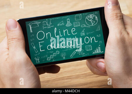 Elevated View Of A Person Holding Smart Phone Showing Online Education Stock Photo