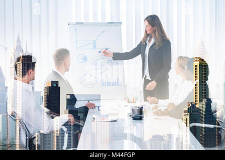Double exposure of businesswoman giving presentation to colleagues amidst buildings Stock Photo