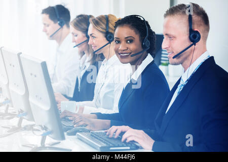 Male and female customer service representatives working at desk seen through glass Stock Photo