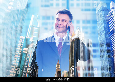 Double exposure of confident businessman talking on mobile phone over city background Stock Photo