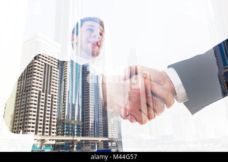 Low angle view of young businessman shaking hand with coworker over city background Stock Photo