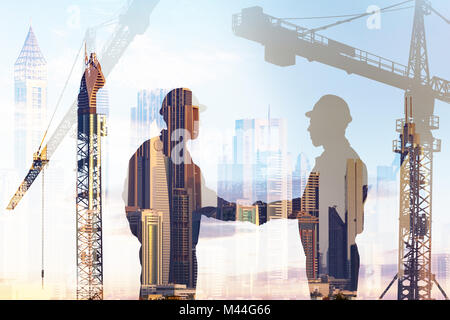 Double exposure of silhouette architects shaking hands over cranes and buildings background Stock Photo