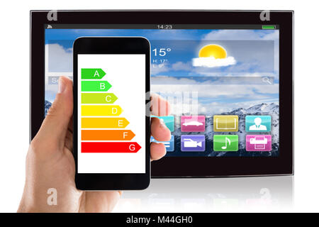 Closeup of man's hand using energy label on mobile phone against television at home Stock Photo