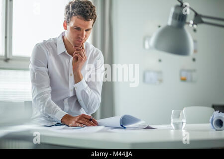 Young businessman analyzing documents in office Stock Photo