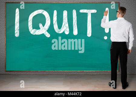 Full length rear view of businessman writing I Quit on blackboard Stock Photo