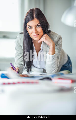 Portrait of confident young female fashion designer working at desk in office