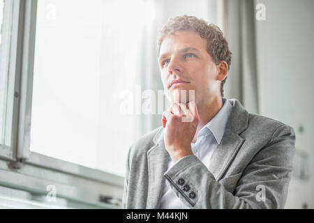 Thoughtful young businessman looking away in office Stock Photo