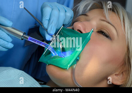 dentist with patient, using dental curing light Stock Photo