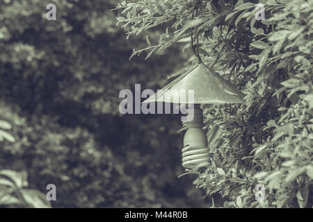 Vintage lamp hanging on green branch trees at outdoor garden in vintage style. Stock Photo