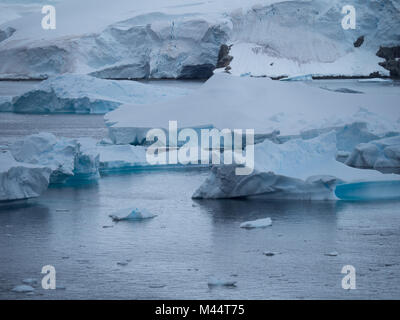 A large iceberg with fissures and ridges floating in Charlotte Bay in Antarctica. The piece of the iceberg has calved off, leaving a jagged edge. Stock Photo