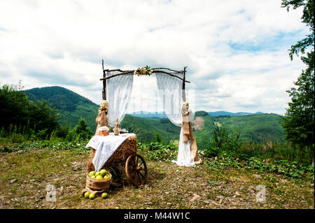 Wedding Arch decorated in rustic style and mountains on the background. Wedding concept. Stock Photo