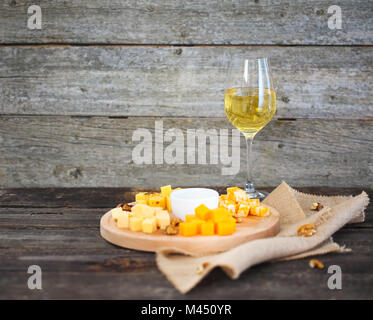 Set of different kind of cheeses with a glass of white wine on the wooden table Stock Photo