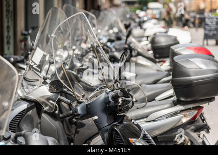 Rows of parked motorbikes and scooters in a street in the city of Bologna Italy Stock Photo