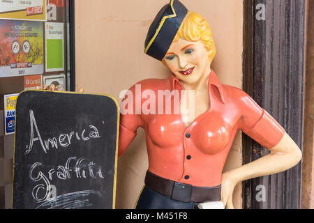 A model of a young woman waitress or manequin outside a bar in Bologna italy withan advertising chalkboard Stock Photo