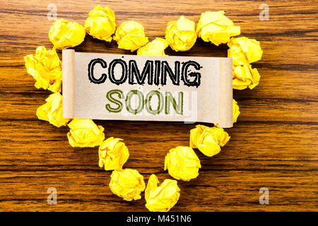 Word, writing Coming Soon. Business concept for Message Future written on sticky note paper on dark wooden background. With yellow folded paper heart  Stock Photo