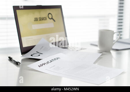 Job seeking in home office. Laptop with online search engine for work. Curriculum vitae or CV and application paper on table. Stock Photo