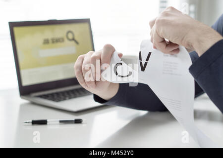 Man ripping his CV and curriculum vitae. Person having problems finding work or writing his job application paper. Angry, frustrated and tired. Stock Photo
