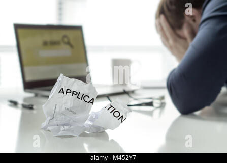 Frustration in job search. Unemployed man cant' find work. Jobless, sad, confused, worried and tired person holding hands on face. Ripped application. Stock Photo