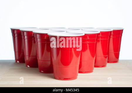 Red party cups on wooden table for beer pong tournament isolated on white. College alcohol containers with free empty blank copy space for text. Stock Photo