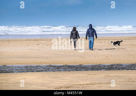 People walking their dog on Perranporth Beach in Cornwall. Stock Photo