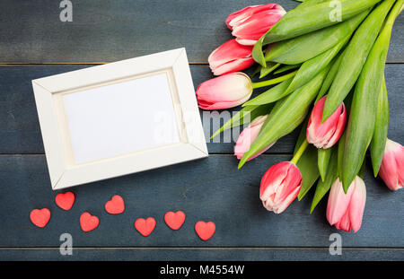 Valentine's day. Pink tulips and an empty white frame on blue wooden background, top view Stock Photo