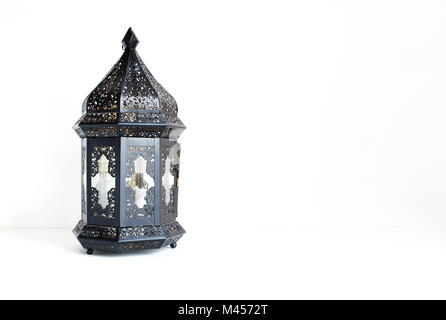 Ornamental dark Moroccan, Arabic lantern on the white table. Greeting card for Muslim community holy month Ramadan Kareem, festive background with a l Stock Photo