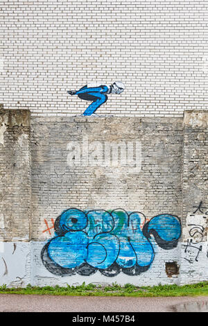 Damaged white bricks wall with ski jumper drawing. Urban art Stock Photo