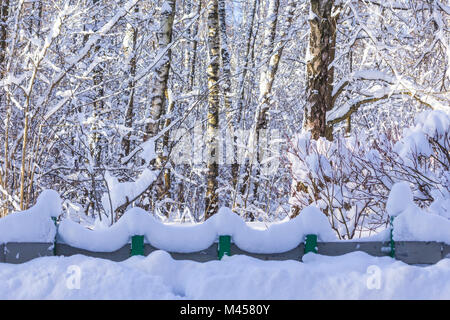 Snowy waves on a decorative fence after a heavy snowfall. An unusual form of snow. Interesting photo for the site about nature, parks and seasons. Stock Photo