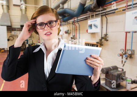 Composite image of redhead businesswoman using her tablet pc Stock Photo