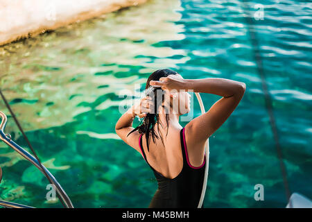 Young woman in bathing costume showering aboard yacht, Croatia Stock Photo