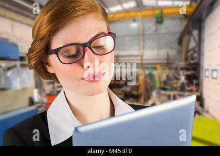 Composite image of redhead businesswoman using her tablet pc Stock Photo