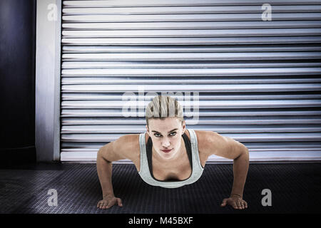 Composite image of muscular woman doing push-ups Stock Photo