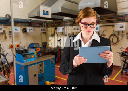 Composite image of redhead businesswoman using her tablet pc Stock Photo