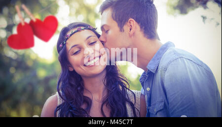 Composite image of cute couple kissing in the park Stock Photo