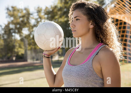 Portrait of woman holding football looking away Stock Photo