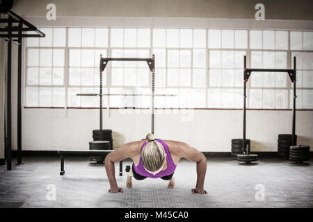 Composite image of muscular woman doing push ups Stock Photo