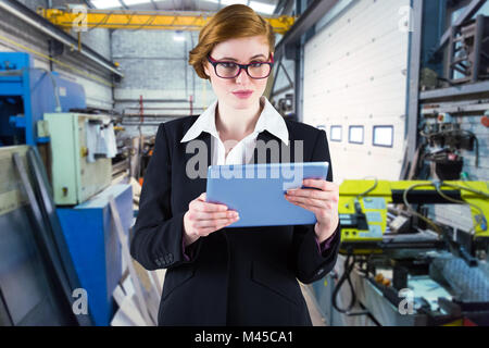 Composite image of redhead businesswoman using her tablet pc Stock Photo