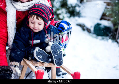 Mother and son in snow on toboggan Stock Photo