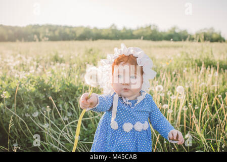 Baby girl in field, holding dandelion Stock Photo