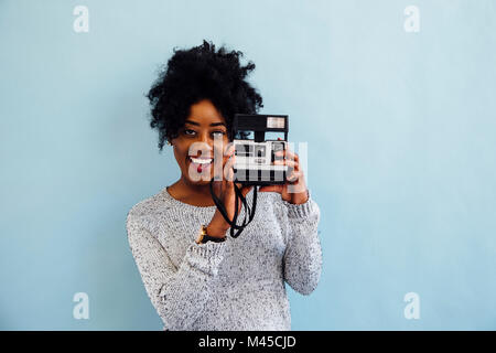 Woman with instant camera looking at camera smiling Stock Photo
