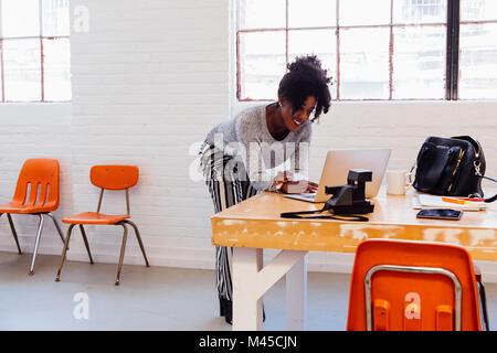 Woman in industrial office building using laptop Stock Photo