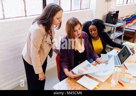 Colleagues in office discussing graphical data on paperwork Stock Photo