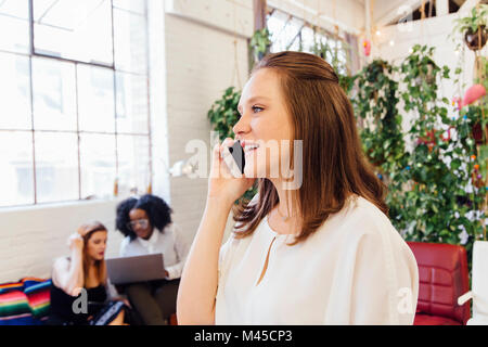 Woman in office making telephone call on smartphone Stock Photo