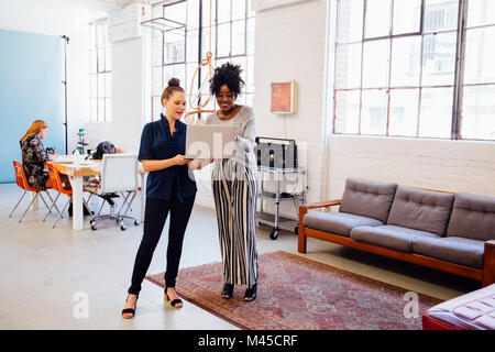 Colleagues in office using laptop together Stock Photo